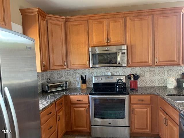 49412 River Run Rd, Albemarle, NC 28001 - kitchen with appliances with stainless steel finishes, backsplash, dark stone countertops, and brown cabinets