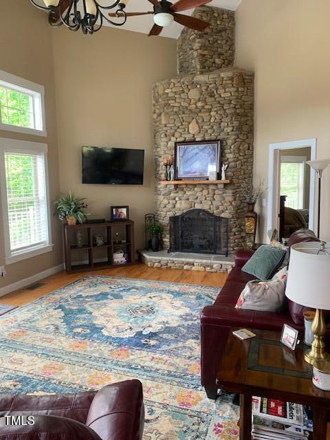 49412 River Run Rd, Albemarle, NC 28001 - living area featuring high vaulted ceiling, a stone fireplace, wood finished floors, ceiling fan, and a chandelier