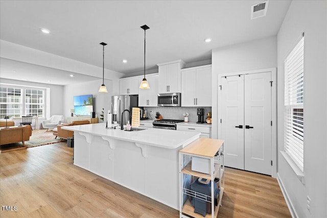 2006 Nola Ln, Durham, NC 27713 - kitchen with stainless steel appliances, a sink, a breakfast bar area, white cabinetry, and light countertops