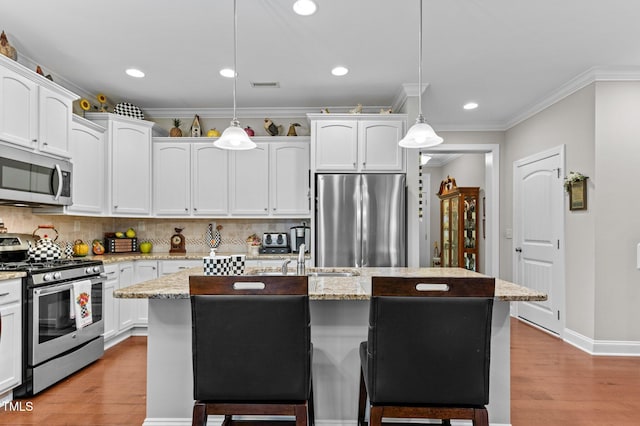 1012 Autumn Meadow Ln, Wake Forest, NC 27587 - kitchen with appliances with stainless steel finishes, a kitchen breakfast bar, light wood-type flooring, backsplash, and white cabinetry