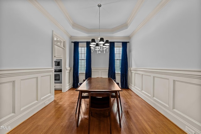 1711 Happiness Hill Ln, Raleigh, NC 27614 - dining area with a chandelier, a raised ceiling, a decorative wall, light wood-style floors, and ornamental molding