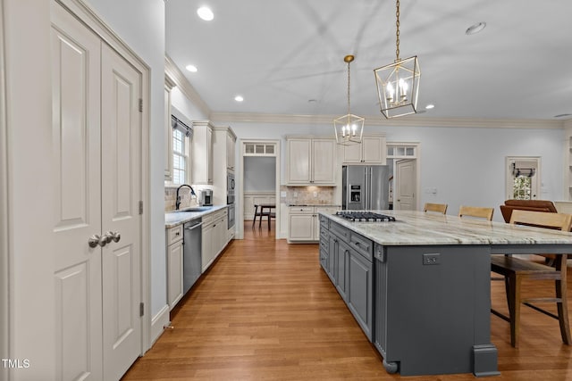 1711 Happiness Hill Ln, Raleigh, NC 27614 - kitchen with stainless steel appliances, gray cabinets, a sink, a breakfast bar, and crown molding