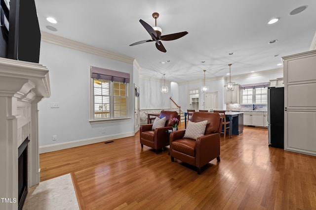 1711 Happiness Hill Ln, Raleigh, NC 27614 - living area featuring a ceiling fan, recessed lighting, ornamental molding, a fireplace with flush hearth, and light wood finished floors
