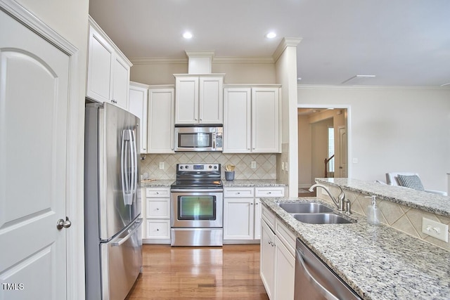 808 Historian St, Raleigh, NC 27603 - kitchen with appliances with stainless steel finishes, white cabinetry, tasteful backsplash, crown molding, and light wood-style flooring