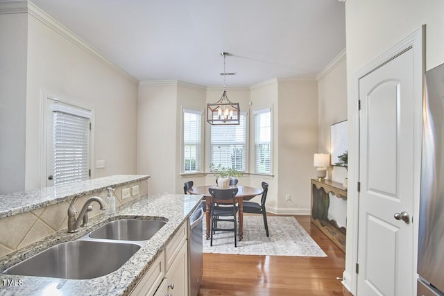 808 Historian St, Raleigh, NC 27603 - kitchen featuring stainless steel dishwasher, a chandelier, wood finished floors, light stone countertops, and pendant lighting