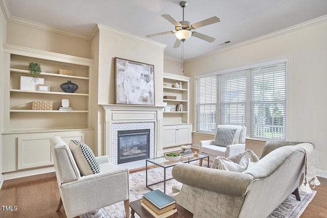 808 Historian St, Raleigh, NC 27603 - living area with wood finished floors, ceiling fan, a fireplace, crown molding, and built in shelves