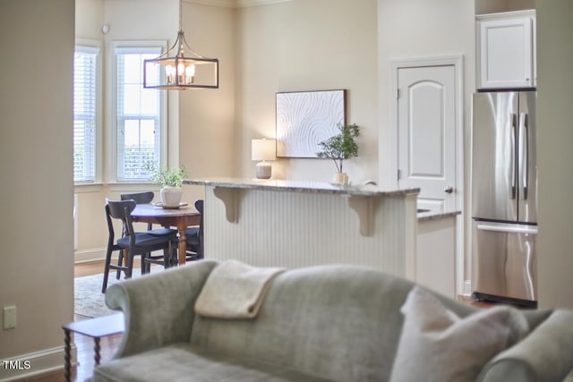 808 Historian St, Raleigh, NC 27603 - kitchen with freestanding refrigerator, a kitchen bar, a chandelier, white cabinetry, and wood finished floors