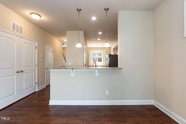 2808 Carter Finley Pl, Raleigh, NC 27606 - kitchen with refrigerator, light stone countertops, a kitchen bar, dark wood-style flooring, and recessed lighting