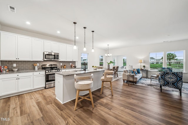 149 Cribbs Ln, Middlesex, NC 27557 - kitchen featuring appliances with stainless steel finishes, light wood-style flooring, a sink, a kitchen island with sink, and decorative backsplash