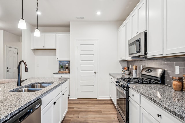 149 Cribbs Ln, Middlesex, NC 27557 - kitchen featuring stainless steel appliances, a sink, light wood finished floors, tasteful backsplash, and white cabinets