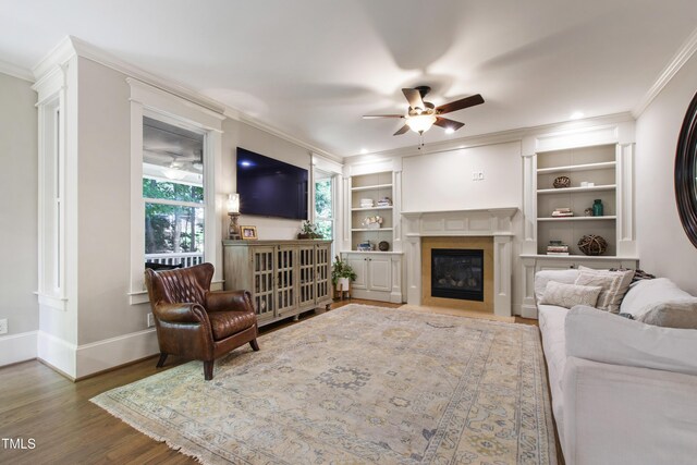 101 Eden Glen Dr, Holly Springs, NC 27540 - living area with ornamental molding, ceiling fan, wood finished floors, a fireplace with flush hearth, and built in features