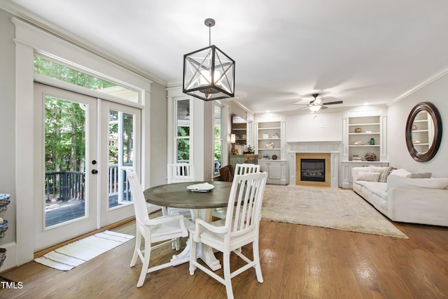 101 Eden Glen Dr, Holly Springs, NC 27540 - dining room featuring crown molding, a ceiling fan, french doors, wood finished floors, and a glass covered fireplace