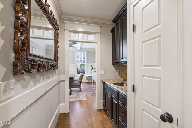 101 Eden Glen Dr, Holly Springs, NC 27540 - bar with light wood-type flooring, crown molding, a sink, wainscoting, and a decorative wall