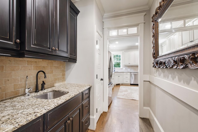 101 Eden Glen Dr, Holly Springs, NC 27540 - bar area with stainless steel appliances, a sink, light wood-style flooring, crown molding, and backsplash