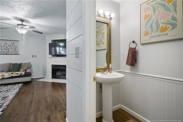 101 Quiet Cv, Raeford, NC 28376 - bathroom with ceiling fan, wood finished floors, a large fireplace, a textured ceiling, and a sink