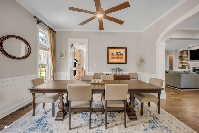 12140 Pawleys Mill Cir, Raleigh, NC 27614 - dining space featuring ceiling fan, a glass covered fireplace, arched walkways, ornamental molding, and wood finished floors
