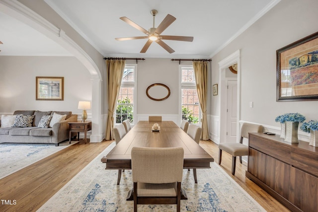 12140 Pawleys Mill Cir, Raleigh, NC 27614 - dining room with light wood-style floors, a ceiling fan, crown molding, arched walkways, and wainscoting