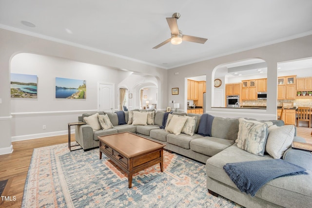 12140 Pawleys Mill Cir, Raleigh, NC 27614 - living room with arched walkways, a ceiling fan, light wood finished floors, ornamental molding, and baseboards