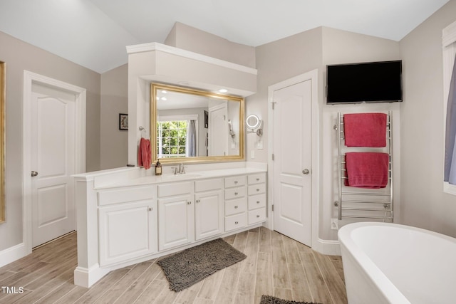 12140 Pawleys Mill Cir, Raleigh, NC 27614 - bathroom featuring a freestanding bath, wood finished floors, vanity, lofted ceiling, and baseboards