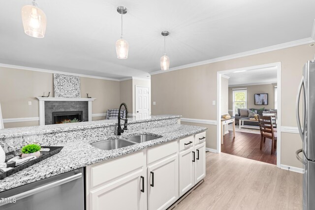 6104 New Market Way, Raleigh, NC 27609 - kitchen featuring a sink, appliances with stainless steel finishes, light wood finished floors, white cabinetry, and hanging light fixtures