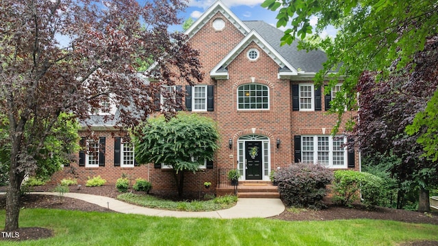 1332 Kinsdale Dr, Raleigh, NC 27615 - georgian-style home with brick siding, a front yard, and a shingled roof