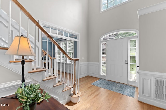 1332 Kinsdale Dr, Raleigh, NC 27615 - foyer entrance featuring a wainscoted wall, wood finished floors, stairs, a high ceiling, and a decorative wall