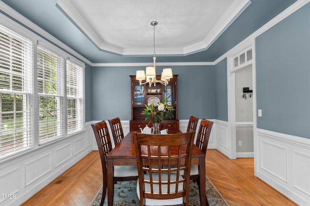 1332 Kinsdale Dr, Raleigh, NC 27615 - dining space featuring a chandelier, a raised ceiling, light wood-style floors, wainscoting, and ornamental molding