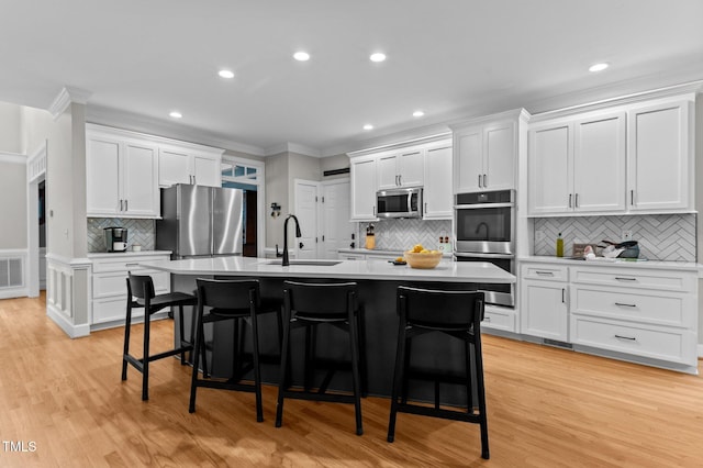 1332 Kinsdale Dr, Raleigh, NC 27615 - kitchen featuring appliances with stainless steel finishes, a sink, backsplash, ornamental molding, and a kitchen bar