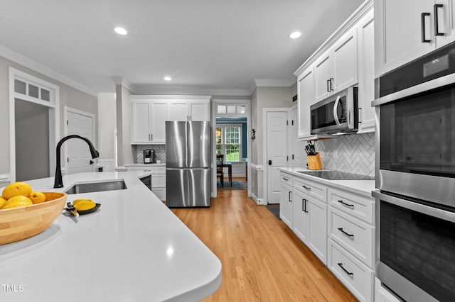 1332 Kinsdale Dr, Raleigh, NC 27615 - kitchen with appliances with stainless steel finishes, a sink, light countertops, ornamental molding, and recessed lighting