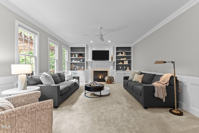 1332 Kinsdale Dr, Raleigh, NC 27615 - carpeted living room featuring crown molding, a ceiling fan, a fireplace, built in features, and a wainscoted wall