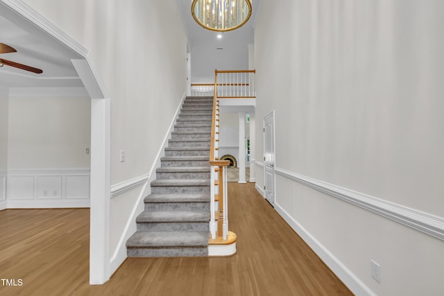 5121 Ten Point Trl, Wake Forest, NC 27587 - staircase with wood finished floors, a ceiling fan, wainscoting, and a chandelier