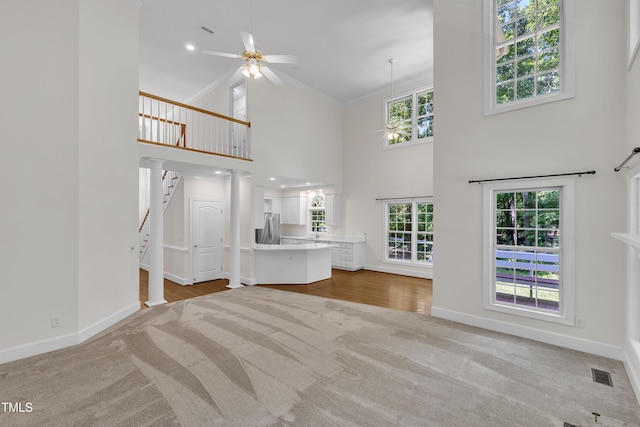 5121 Ten Point Trl, Wake Forest, NC 27587 - unfurnished living room featuring a ceiling fan, carpet, a high ceiling, crown molding, and stairway