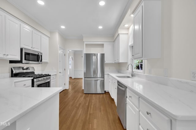 5121 Ten Point Trl, Wake Forest, NC 27587 - kitchen featuring appliances with stainless steel finishes, a sink, crown molding, white cabinetry, and light wood finished floors