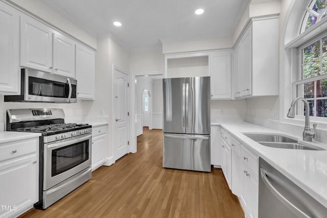 5121 Ten Point Trl, Wake Forest, NC 27587 - kitchen featuring appliances with stainless steel finishes, a sink, light wood-type flooring, white cabinetry, and crown molding