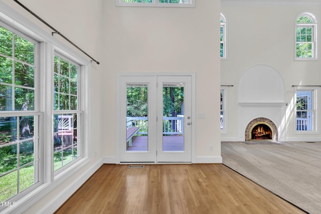5121 Ten Point Trl, Wake Forest, NC 27587 - unfurnished living room featuring a towering ceiling, baseboards, plenty of natural light, wood finished floors, and a fireplace