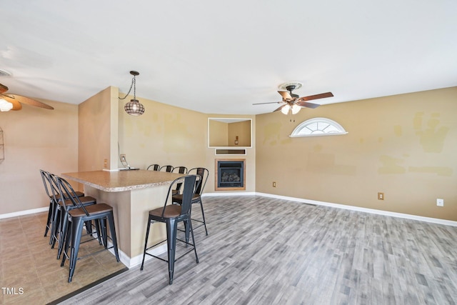 102 Pine St, Dunn, NC 28334 - kitchen featuring ceiling fan, a kitchen bar, baseboards, and light wood-style floors