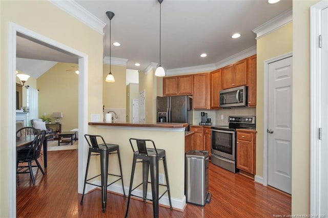 15 London Way, Spring Lake, NC 28390 - kitchen with appliances with stainless steel finishes, a breakfast bar, crown molding, tasteful backsplash, and brown cabinets