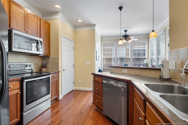 15 London Way, Spring Lake, NC 28390 - kitchen featuring stainless steel appliances, crown molding, a sink, decorative backsplash, and brown cabinets