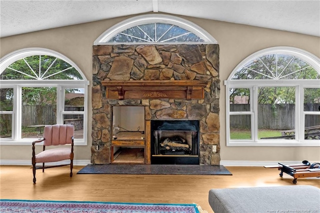 114 Birch Cir, Raeford, NC 28376 - living area with plenty of natural light, vaulted ceiling, a stone fireplace, wood finished floors, and a textured ceiling
