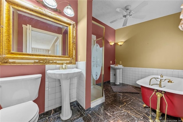 114 Birch Cir, Raeford, NC 28376 - full bathroom featuring tile walls, marble tiled flooring, wainscoting, a stall shower, and toilet