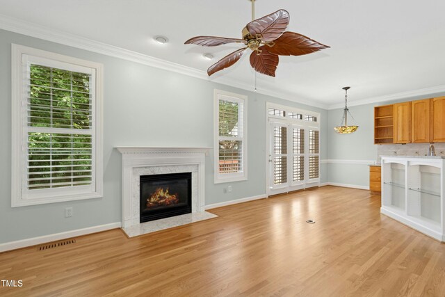 1003 Blackberry Ln, Durham, NC 27712 - unfurnished living room with plenty of natural light, crown molding, a fireplace, light wood-style floors, and ceiling fan