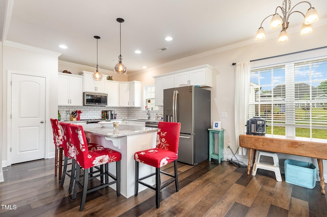 1828 Wellspring Ct, Graham, NC 27253 - kitchen with stainless steel appliances, a center island, dark wood-style floors, white cabinets, and ornamental molding