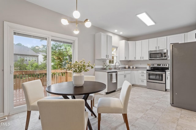 8912 Erinsbrook Dr, Raleigh, NC 27617 - kitchen featuring appliances with stainless steel finishes, healthy amount of natural light, white cabinets, light countertops, and recessed lighting