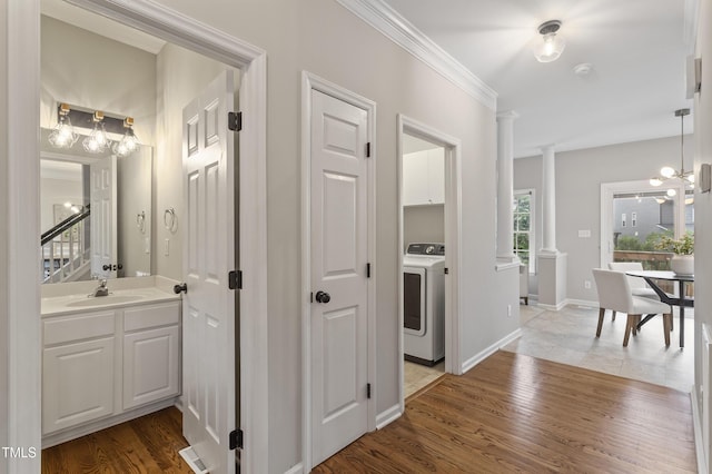 8912 Erinsbrook Dr, Raleigh, NC 27617 - hallway with washer / clothes dryer, a sink, a chandelier, ornate columns, and crown molding