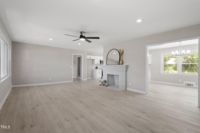 2003 Broadway Rd, Sanford, NC 27332 - unfurnished living room featuring a chandelier, ceiling fan, light wood-type flooring, baseboards, and a brick fireplace