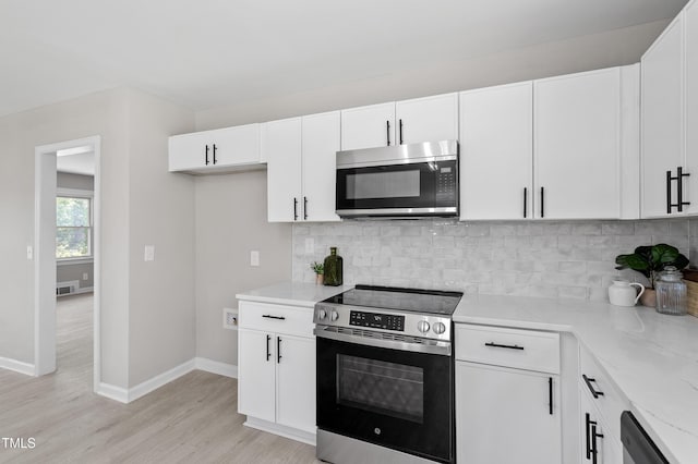 2003 Broadway Rd, Sanford, NC 27332 - kitchen featuring stainless steel appliances, light wood finished floors, decorative backsplash, white cabinets, and baseboards
