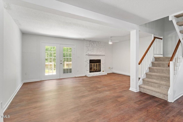 134 Luxon Pl, Cary, NC 27513 - unfurnished living room with a textured ceiling, wood finished floors, stairs, a stone fireplace, and a ceiling fan