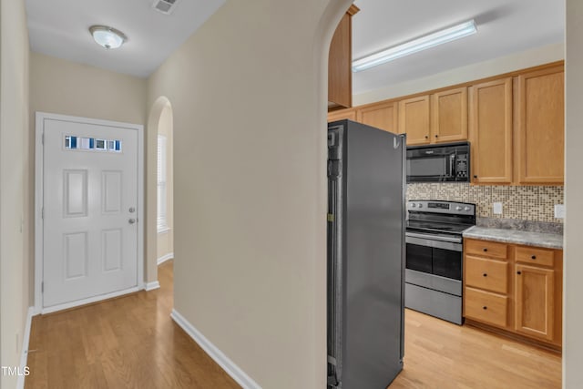 2513 Asher View Ct, Raleigh, NC 27606 - kitchen with electric range, black microwave, freestanding refrigerator, arched walkways, and light wood-style flooring