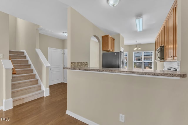 2513 Asher View Ct, Raleigh, NC 27606 - kitchen with appliances with stainless steel finishes, dark wood finished floors, decorative light fixtures, baseboards, and brown cabinetry
