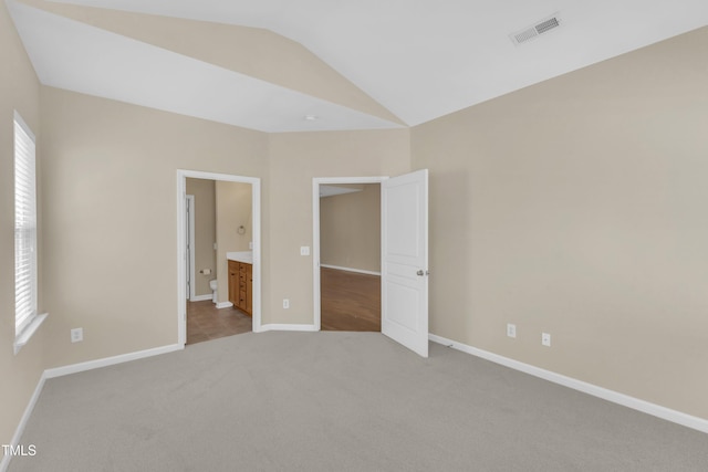 2513 Asher View Ct, Raleigh, NC 27606 - unfurnished bedroom with carpet, lofted ceiling, baseboards, multiple windows, and connected bathroom